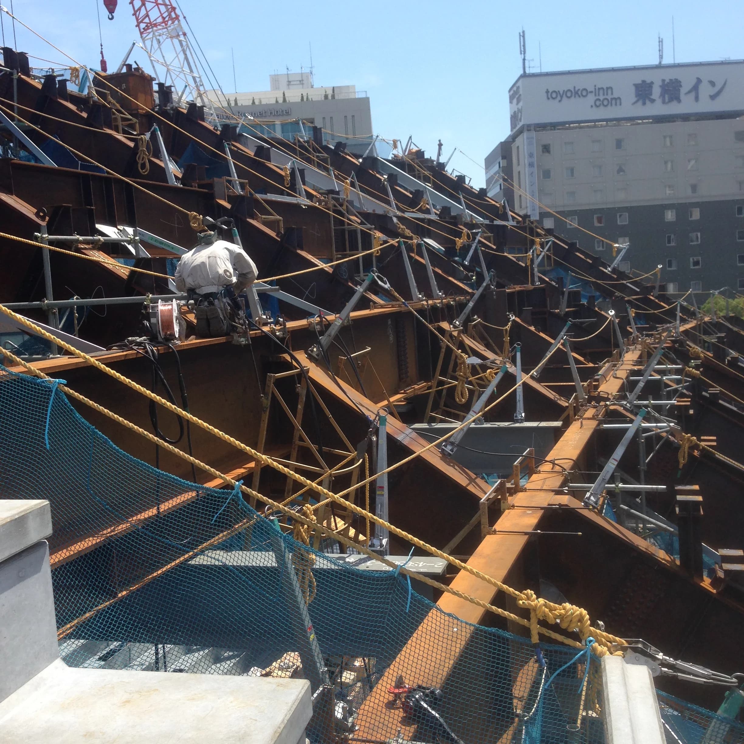 夕景の鉄骨建方現場を歩く鳶職人